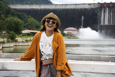 Portrait of young woman standing against waterfall