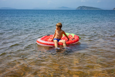 Rear view of shirtless boy in sea