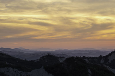 Scenic view of mountains against dramatic sky during sunset