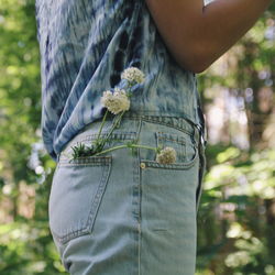 Midsection of woman with flowers in pocket