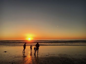 Silhouette people at beach during sunset