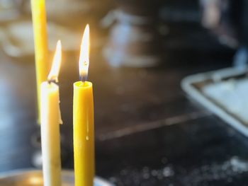 Close up of two burning candles on the wooden background with blurred background with copy space