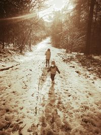 Rear view of girl walking on snow covered forest