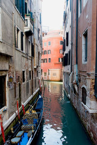 Boats moored in canal amidst buildings