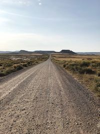 Road leading towards landscape against sky