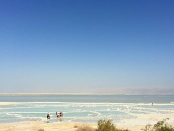 People at dead sea against clear blue sky