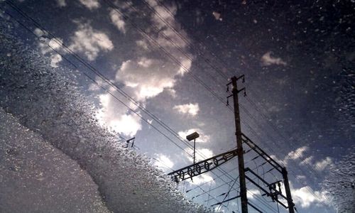 Low angle view of power lines against cloudy sky