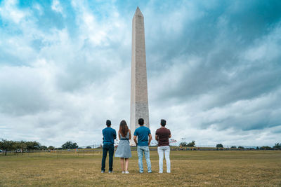 People standing on field against cloudy sky