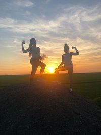 Silhouette people on field against sky during sunset