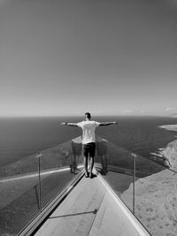 Rear view of man standing by sea against sky