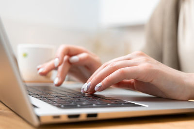 Close up photo of pretty woman hands typing on laptop keyboard. female freelancer working from home.