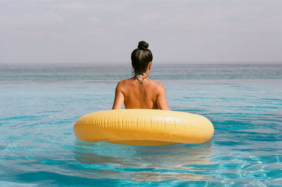 Rear view of shirtless man looking at sea
