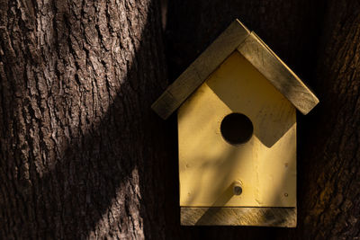 Close-up of birdhouse on tree trunk against wall