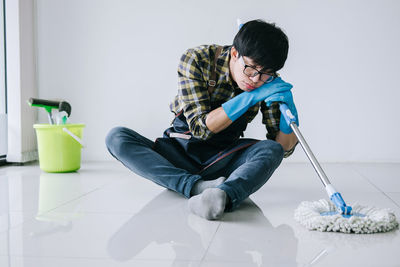 Tired man cleaning floor at home
