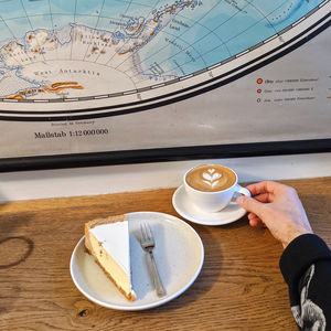 High angle view of hand holding coffee cup on table