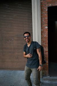 Full length portrait of young man standing against wall