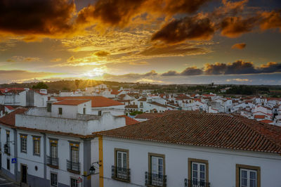 Houses in town against sky during sunset