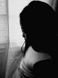 Rear view of young woman standing against wall