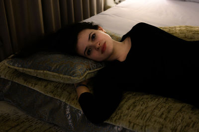 Portrait of woman lying on bed at home