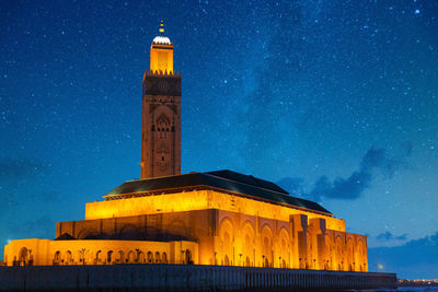 Illuminated historic mosque on sea against star field