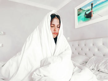 Young woman sitting on bed