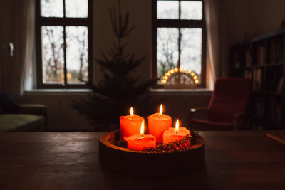 Close-up of lit tea light candles on table at home