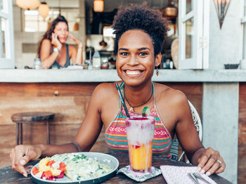 Portrait of smiling young woman having food and drink in restaurant