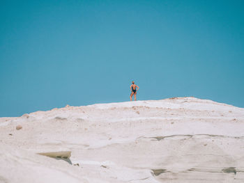Low angle view of woman standing on white cliffs against blue sky