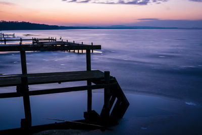 Pier on sea against sky during sunset