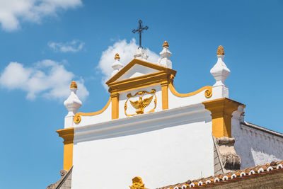 Low angle view of cross by building against sky