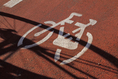Signage on the cycle path, ocher-colored road surface, shadow of a bicycle.