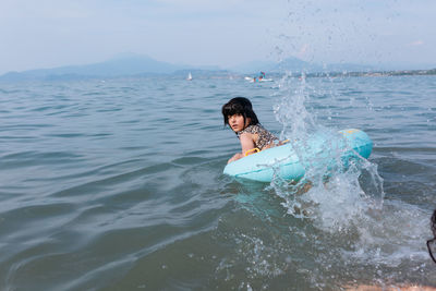 Girl swimming in the water with the help of inflatable ring making splashes