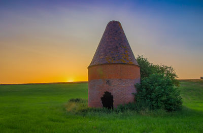 Built structure on field against sky during sunset