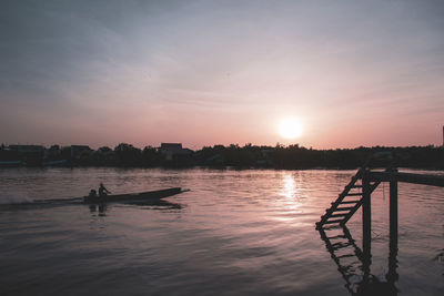 Silhouette boat in lake against sky during sunset