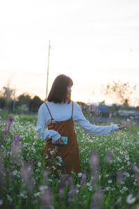 Rear view of woman standing on field against sky