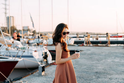 Woman with umbrella standing on boat in sea against sky