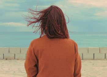 Rear view of woman standing at beach