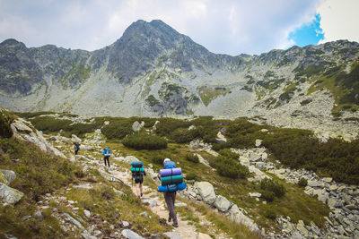 Rear view of people walking on mountains against sky