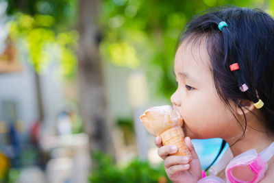Cute girl licking ice cream outdoors