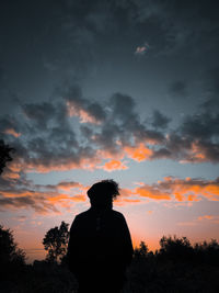 Rear view of silhouette man looking at sunset