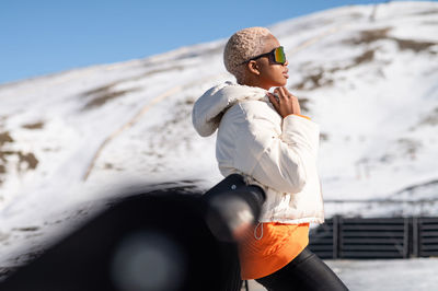 A young african american woman wearing sunglasses having fun in the snow on a winter day