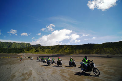 People riding motorcycle on road against sky