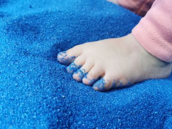 Close view of baby feet touching blue sand.