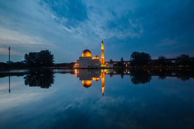 Reflection of church in lake against cloudy sky