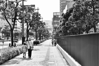 Rear view of people walking on footbridge in city