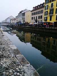Reflection of buildings in puddle against clear sky