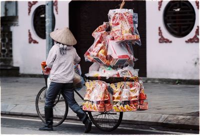 Rear view of street vendor carrying toys on bicycle