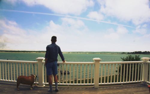 Man with dog walking on railing against sea