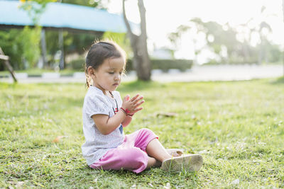 Side view of young woman sitting on field