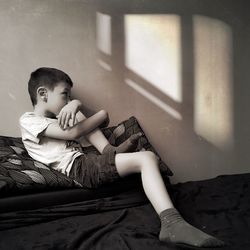 Boy sitting on bed at home